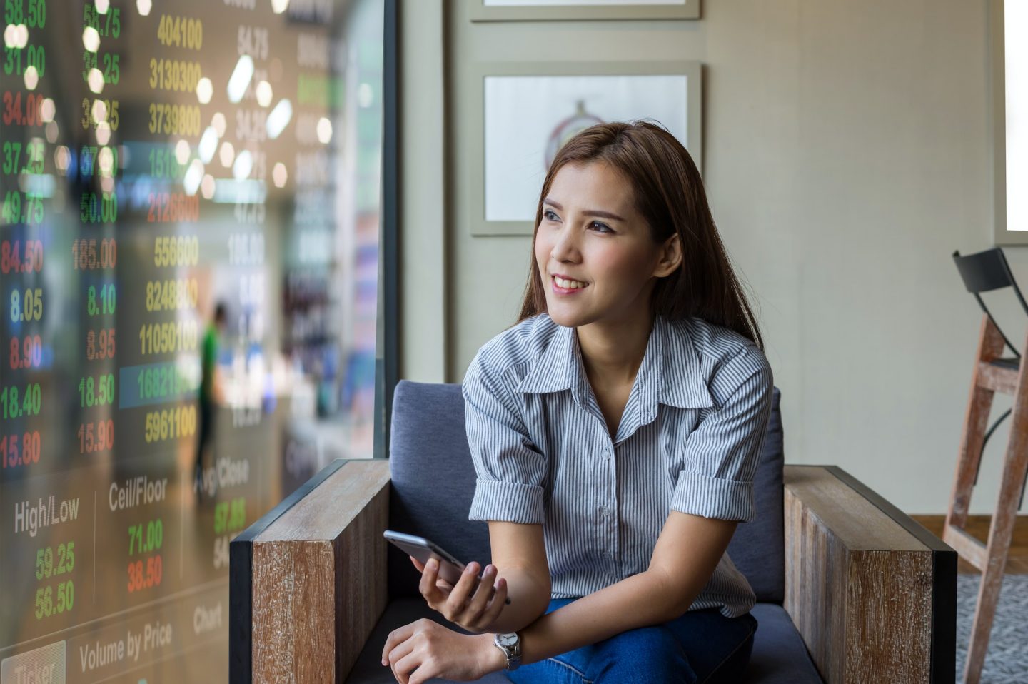 Happy asian businesswoman sitting on working space and looking the trading graph